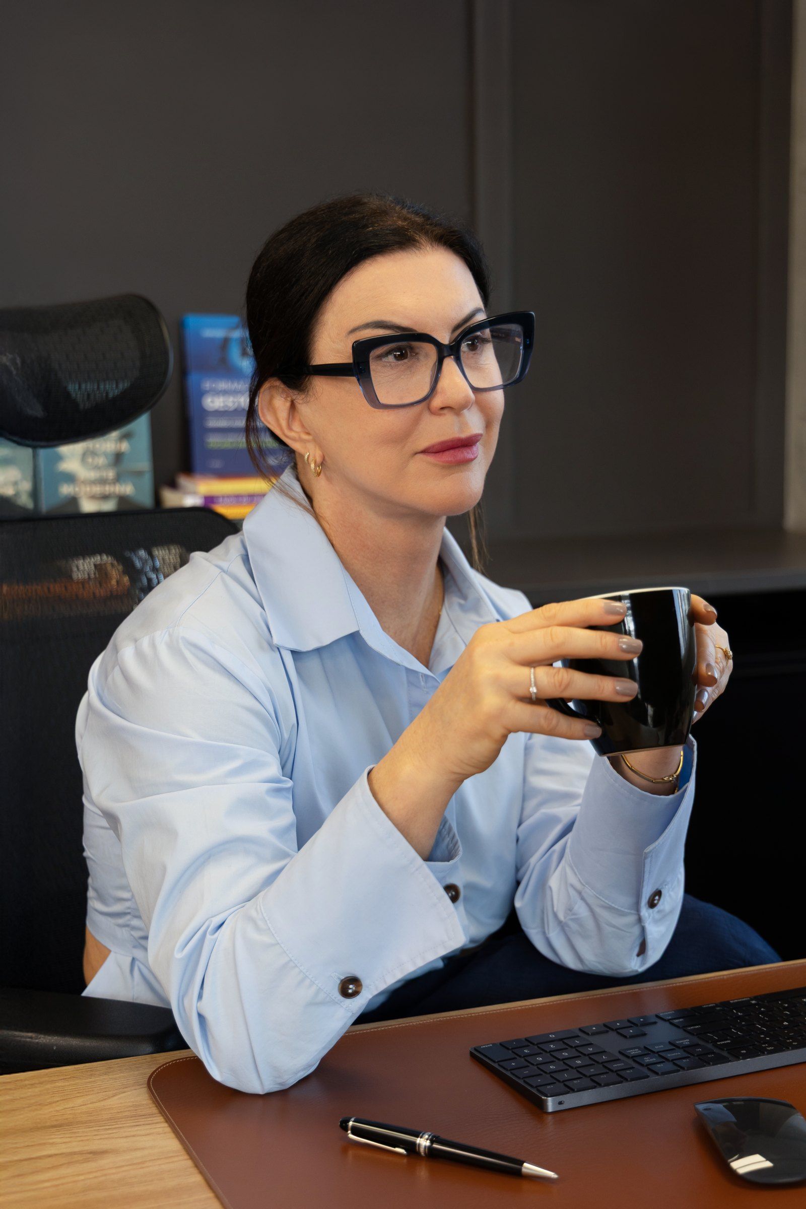 Raquel Araújo em sua mesa, segurando uma xícara de café